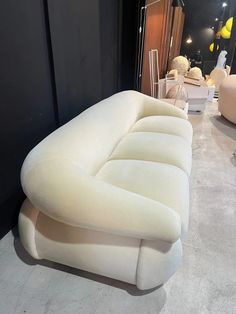 a large white couch sitting on top of a floor next to a chair and table