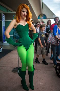 a woman dressed in green poses for the camera with other people behind her and onlookers