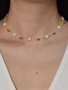 a woman wearing a necklace with daisies and pearls on the bottom of her neck