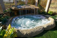 an outdoor hot tub in the middle of a garden with water running down it's sides