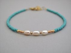 a bracelet with pearls and gold beads on a blue string, sitting on a table