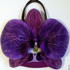 a purple flower with a black handle hanging from it's side on a white wall