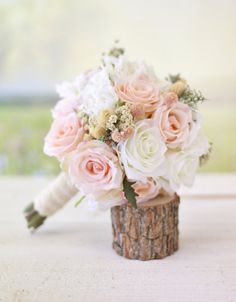 a bouquet of pink and white flowers sitting on top of a tree stump