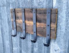 three metal hooks are attached to a wooden wall with some wood planks on it