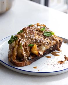 a piece of bread on a plate with sauce and herbs sprinkled all over it