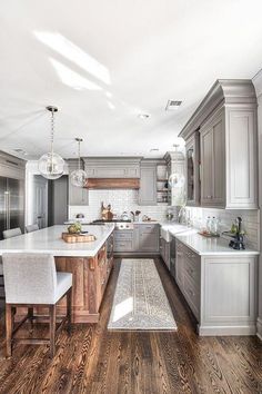 a large kitchen with wooden floors and gray cabinets, white counter tops, and an island in the middle