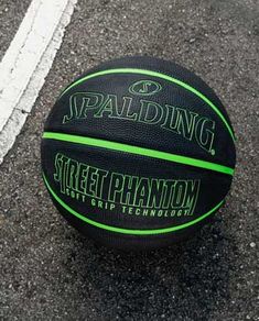 a black and green basketball sitting on top of a parking lot next to a white line