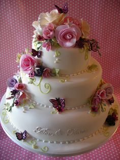 a three tiered wedding cake decorated with flowers and butterflies