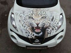 a white car with an image of a leopard painted on it's front hood