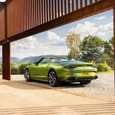 a green sports car parked under a wooden structure