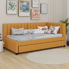 an orange daybed with lots of pillows and pictures on the wall