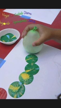 a child's hand is painting on paper with watercolors