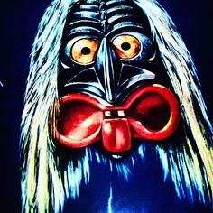 a painting of a man with long hair wearing a black mask and red bow tie