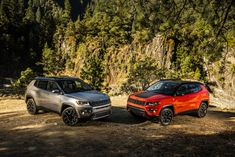 two jeeps parked next to each other in the woods