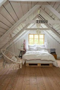 an attic bedroom with white walls and wooden floors, a hammock hanging from the ceiling