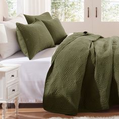 a bed with green bedspread and pillows on it