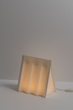 a lamp that is sitting on top of a white surface with a cord attached to it