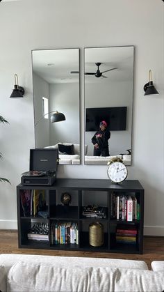 a mirror sitting on top of a black shelf next to a white couch in a living room