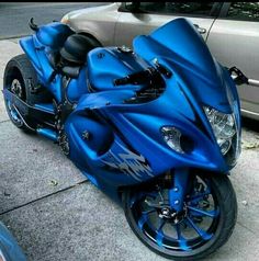 a blue motorcycle parked next to a silver car