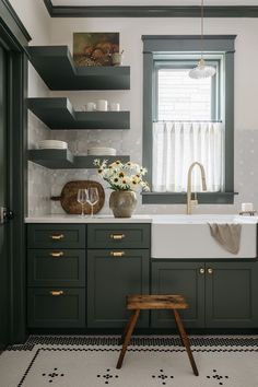 a kitchen with dark green cabinets and white counter tops, an open window above the sink