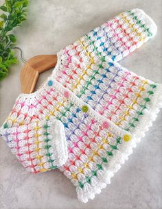 a crocheted dishcloth and wooden spoon rest on a marble surface next to green plants