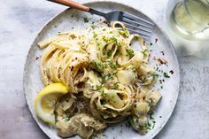 a white plate topped with pasta and lemon wedges