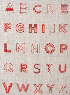 an embroidered alphabet is shown with red thread on the upper and lower letters, which have been stitched together
