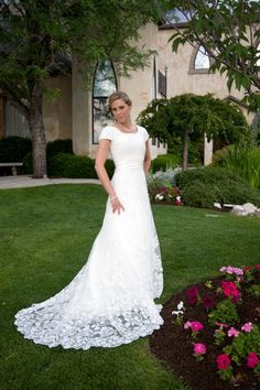 a woman in a wedding dress standing on the grass