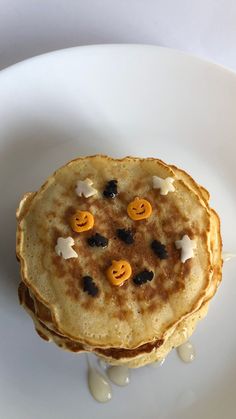 pancakes decorated with jack - o'- lantern faces on a white plate