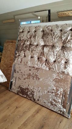 a large piece of metal sitting on top of a wooden floor next to a pile of plywood