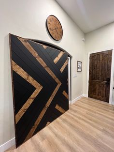 a clock on the wall next to a wooden door in a room with hard wood flooring