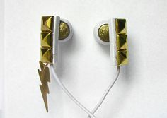 two earbuds with gold and white designs on them, one has a lightning bolt