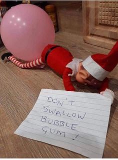 an elf is lying on the floor next to a sign that says don't swahlow bubble gum