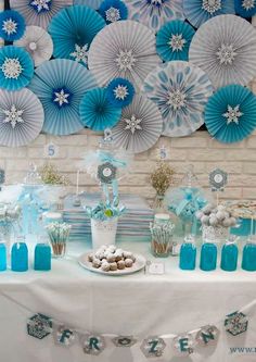 a table topped with lots of blue and white paper fan decorations on top of it