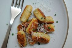 a white plate topped with ravioli and parmesan cheese next to a fork