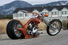 an orange motorcycle is parked on the side of the road in front of some houses