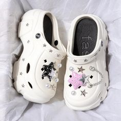 two white clogs with stars and pearls on them sitting on top of a bed