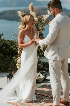 a man and woman standing next to each other in front of a wedding ceremony arch