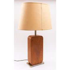 a wooden table lamp with a beige shade on the base and a light bulb plugged in