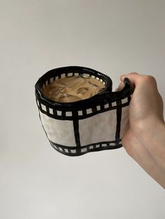 a hand holding a black and white cup filled with liquid in it's sleeve