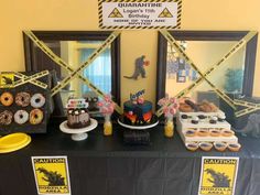 a table topped with cakes and donuts covered in yellow caution tape next to framed pictures