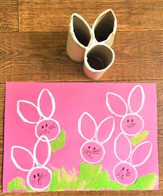 a pink paper with some bunny faces drawn on it next to two rolled up eggs