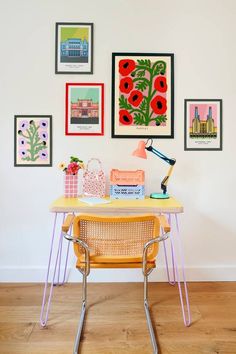 a table with some pictures on the wall above it and a chair in front of it