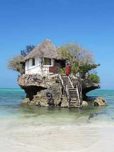 an island with stairs leading to a house on top of it in the middle of the ocean