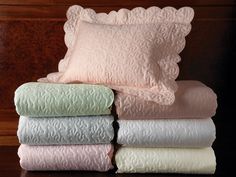 a stack of pillows and blankets sitting on top of a wooden table next to each other