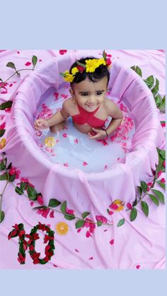 a baby sitting in a pool with flowers on it