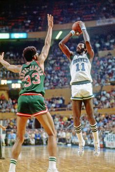 the basketball player is jumping up to dunk the ball in front of the other player