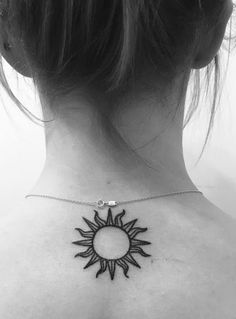 a woman's back neck with a sun tattoo on it