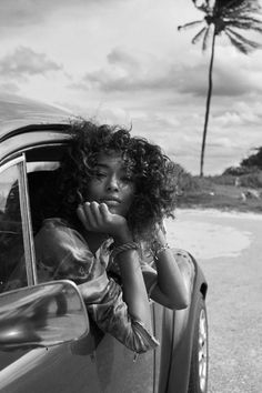 a woman leaning out the window of a car with her hand on her chin and looking at herself