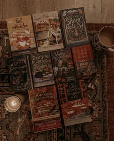 a pile of books sitting on top of a rug next to a cup of coffee